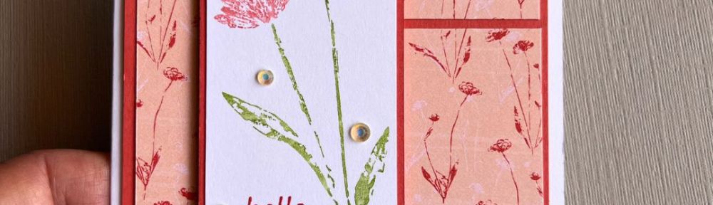 handmade card with two flowers and a printed paper background on a white card base with the sentiment "hello friend"