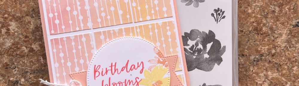 A Handmade card with a printed background and a floral circular element with the phrase “Birthday Blooms for you”