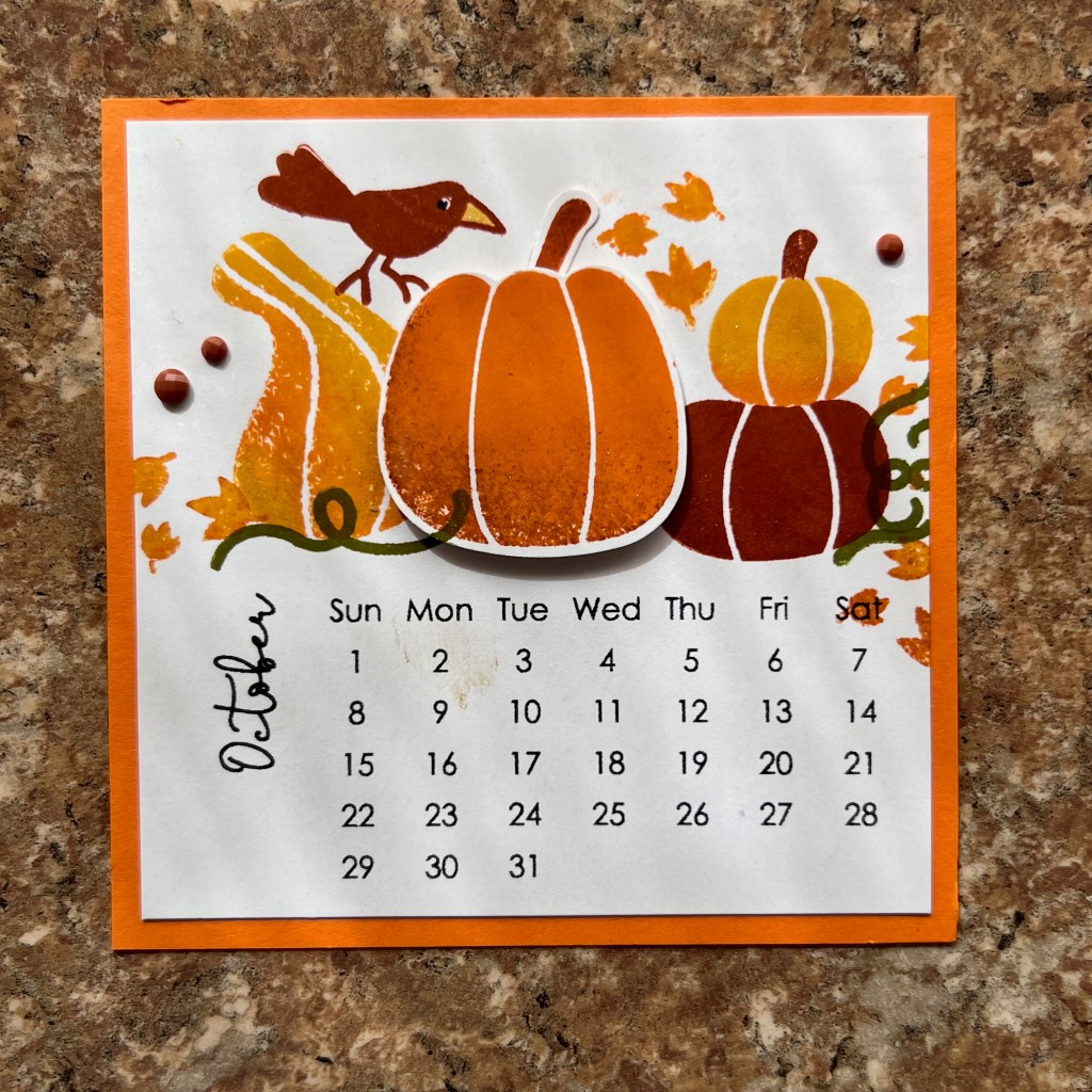 A small square calendar for October 2023 with 4 pumpkins and a small bird.