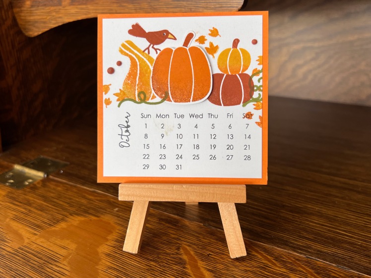 A small square calendar for October 2023 with 4 pumpkins and a small bird.